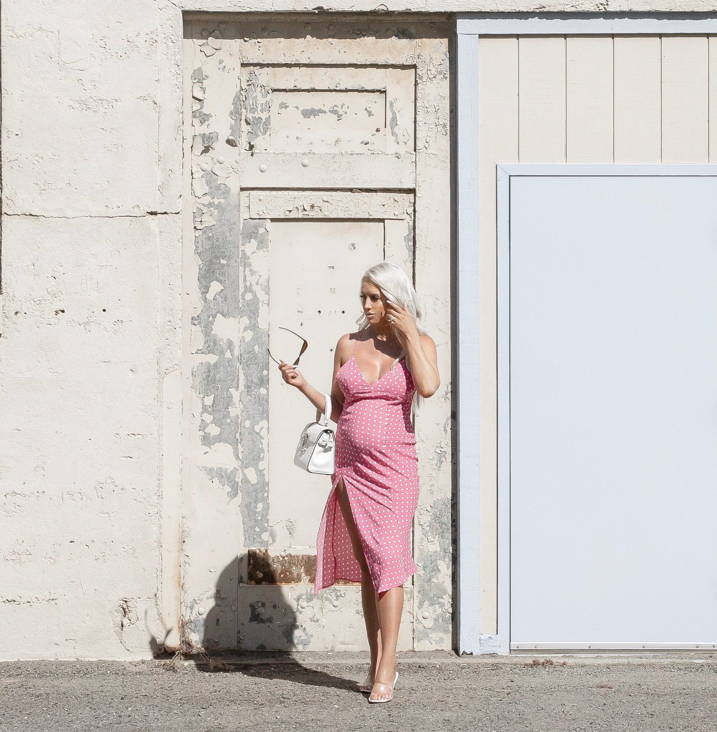 Fashion blogger a pink poka dot midi dress and white kitten heels